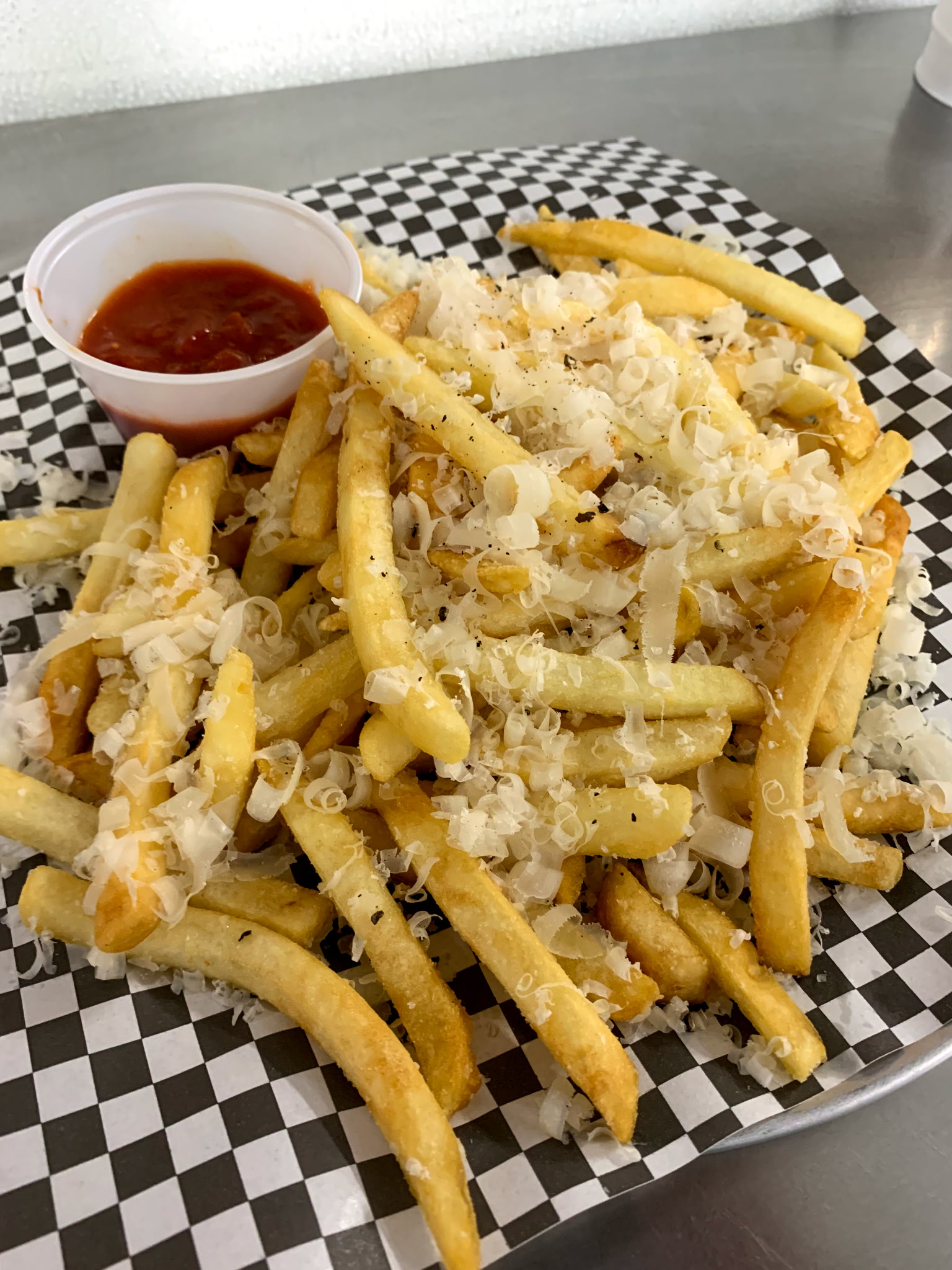 Parmigiano fries with marinara dipping sauce on checkered paper